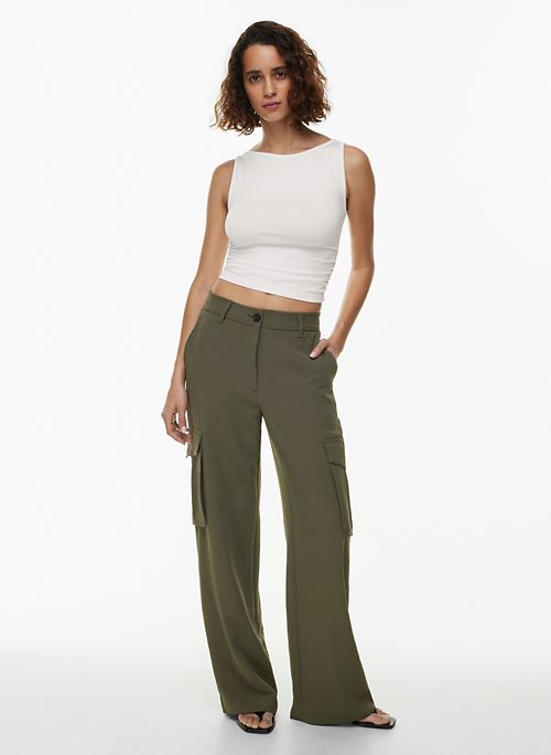 Full length photo of friendly positive woman wear green shirt white pants  look at promotion empty space isolated on beige color background Stock  Photo - Alamy